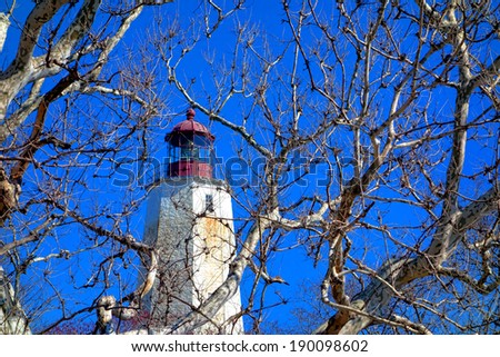 Sandy Hook historic lighthouse coastal maritime navigation aid guiding light through winter trees branches at the Gateway National Recreation Area of the US Park Service on the coast of New Jersey