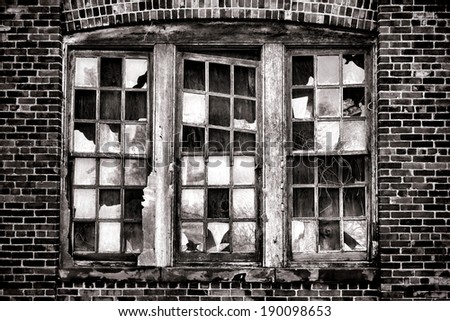 Broken window with missing glass panes and antique brick wall on an old abandoned industrial warehouse building in a derelict blight factory