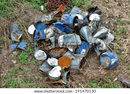 Pollution junk trash pile of discarded empty industrial waste oil and chemical steel cans and aluminum drums abandoned in unsafe environment polluted waste site and waiting for recycling safe reuse
