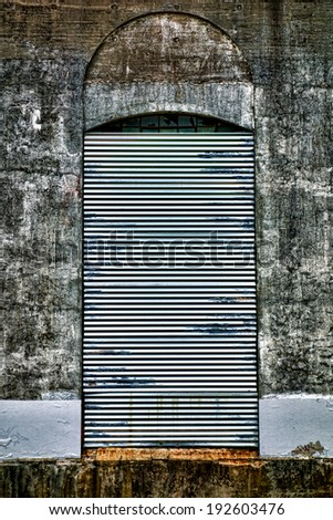Heavy duty steel roll up curtain security door blocking entry access to an opening access bay in an abandoned factory building loading dock
