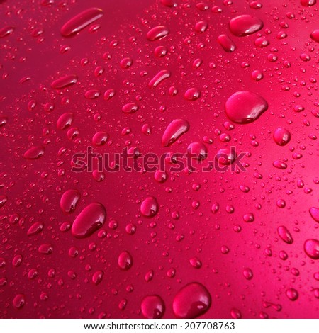 Water drops and droplets on a pink metallic paint car wet surface after the rain background