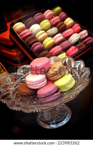 Macaroon cake in pastel colors on a confection glass serving dish with gift box assortment on a store display in a fancy biscuit and cookie shop