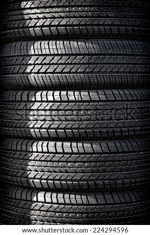 Stack tower of new passenger automobile car tires with all weather thread in a vertical pile for display and sale at an auto wheel repair shop