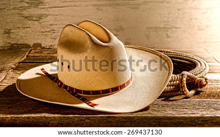 American West rodeo cowboy traditional white straw hat on an old wood table in an antique western rancher barn lit by soft diffused Laredo morning light