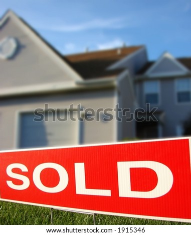 Real estate sold sign rider on Realtor advertising sign in front of a house for sale