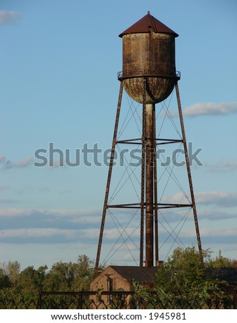 Old and rusty abandoned industrial water tower with reservoir tank on a Brownfield factory recovery site