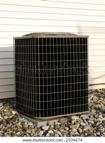 Residential air conditioner condenser unit outside a house as part of a climate control cooling and refrigeration conditioning system
