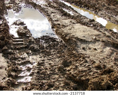 Muddy Road with bulldozer tracks in the mud and water puddle on a construction site