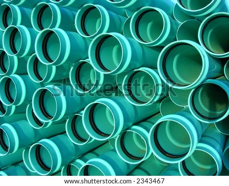 Stack of new green PVC storm sewer drainage pipes ready for a waste water drain  management project on a housing construction site