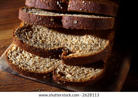 Sliced country style whole wheat grain bread on a wood cutting board
