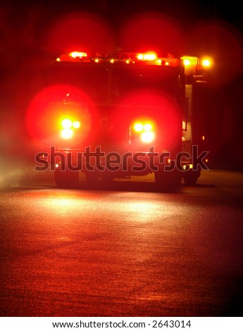 Speeding fire truck with flashing emergency warning lights driving fast to a disaster response scene on a street at night