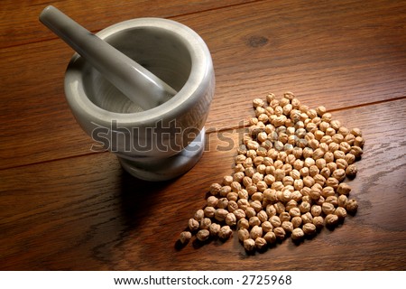 Traditional medicine preparation tools with marble mortar and grinding pestle and spilled natural grains on wood