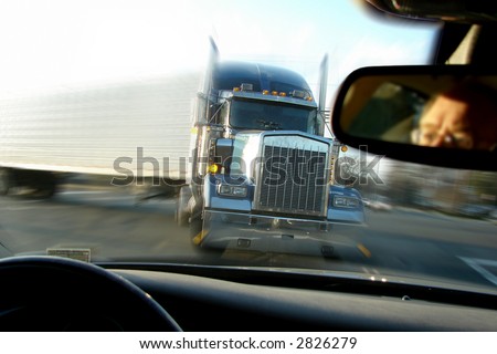 Close call imminent crash accident with a tractor trailer truck viewed from inside a passenger car with scared driver face in rear view mirror