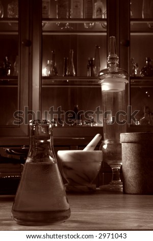 Vintage glassware and old pharmacy equipment in antique science research lab with apothecary style medicine case filled with ancient medical glass vials in nostalgic vintage sepia