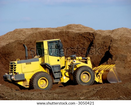 Heavy duty articulated excavator working in a pile of fresh dirt on a construction site
