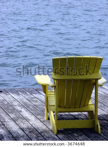 Empty yellow Adirondack chair on a dock over the water