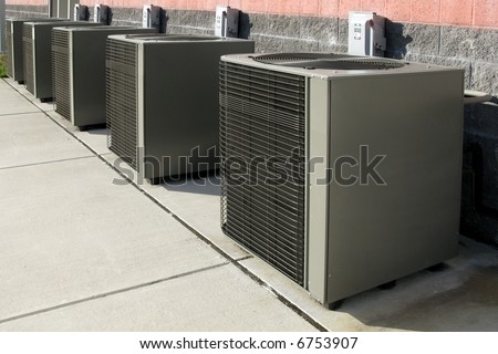 Row of commercial HVAC air conditioner outside condenser units outside a commercial building as part of a climate control cooling and refrigeration conditioning system