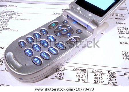 Open and lit clam shell flip style cell phone on bank statement