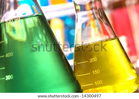 Laboratory glass conical Erlenmeyer flasks filled with yellow and green chemical liquid for an experiment in a science research lab