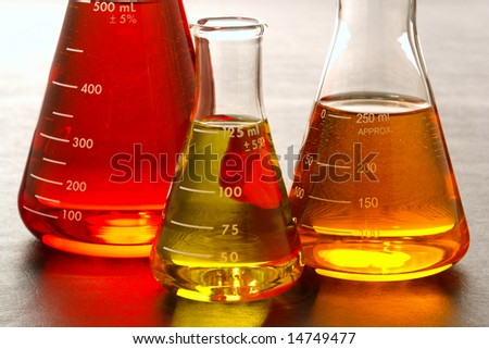 Laboratory glass conical Erlenmeyer flasks filled with red and orange chemical liquid for an experiment in a science research lab