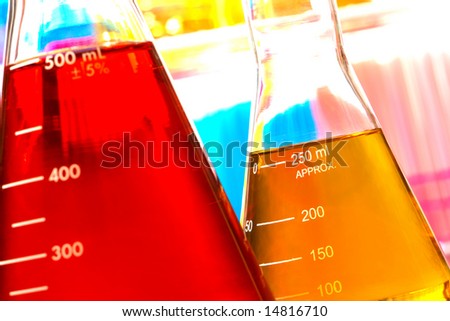 Laboratory glass conical Erlenmeyer flasks filled with red and orange liquid chemical and orange color solution for an experiment in a science research lab