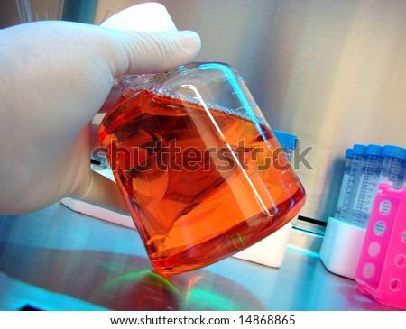 Scientist hand holding a laboratory glass container filled with red chemistry liquid in a science research lab