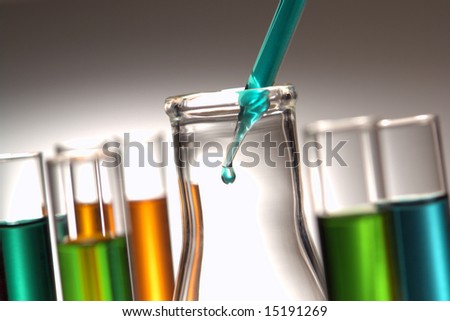 Laboratory pipette with drop of blue chemical solution inside a glass conical Erlenmeyer flask for an experiment in a science research lab Laboratory pipette with drop of blue chemical solution inside a glass conical Erlenmeyer flask for an experiment in a science research lab