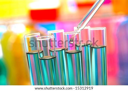 Laboratory pipette with drop of liquid over glass test tubes for an experiment in a science research lab