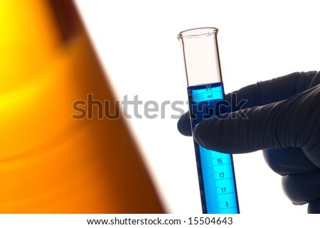 Scientist hand holding a scientific laboratory graduated cylinders filled with blue liquid for an experiment in a science research lab