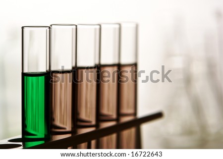 Laboratory glass test tubes filled with green and brown liquids on a rack for an experiment in a science research lab