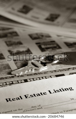 Real estate listing contract and key over newspaper open on house for sale classified section