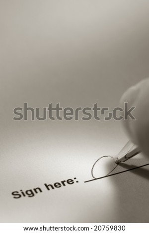 Fingers holding a pen and signing a document on the signature line