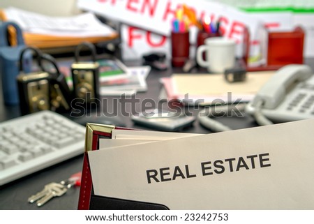Blank document in an agent presentation binder with real estate title page over successful and busy Realtor desk in realty brokerage sales office with tools of the trade and business supplies