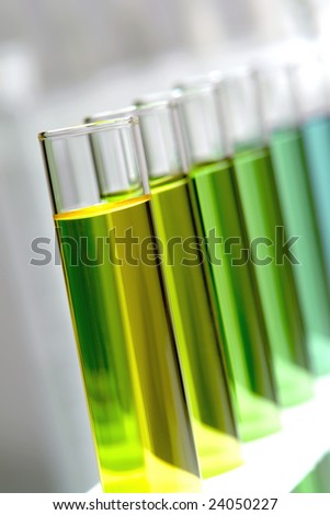 Laboratory glass test tubes filled with green and yellow liquid chemical on a rack for an experiment in a science research lab