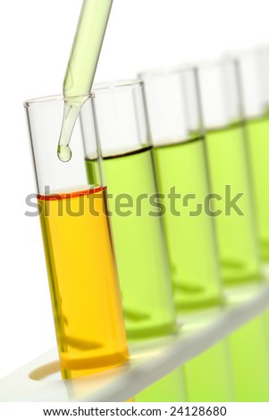 Laboratory pipette with drop of liquid inside test tube filled with orange liquid and other tubes full of green chemical solution on a rack for an experiment in a science research lab