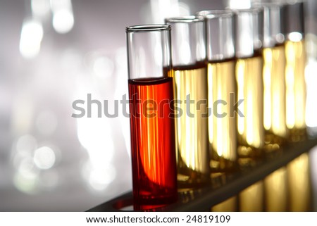 Laboratory glass test tubes filled with red and gold color liquid on a rack for an experiment in a science research lab
