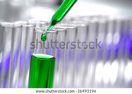 Laboratory pipette with drop of green liquid inside test tubes for an experiment in a science research lab