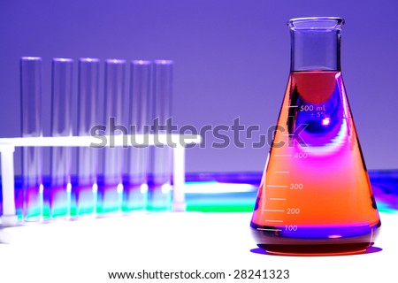 Scientific laboratory glass conical Erlenmeyer flask filled with red chemical liquid and test tubes in a rack for a chemistry experiment in a science research lab