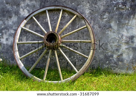 Old Conestoga wagon wood wheel against an old house wall
