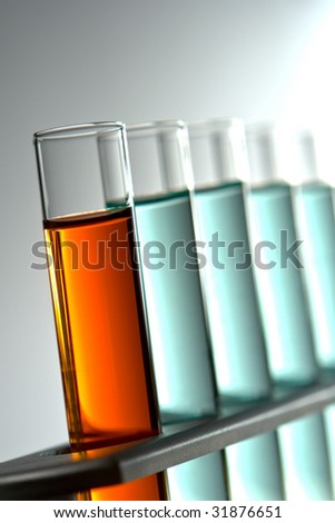 Laboratory glass test tubes filled with red liquid and blue chemical solution on a rack for an experiment in a science research lab