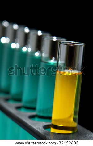Laboratory glass test tubes filled with yellow liquid and green chemical solution on a rack for an experiment in a science research lab