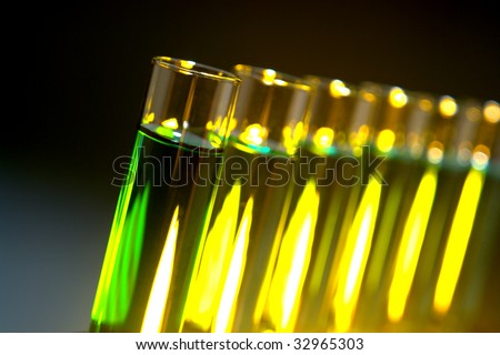 Laboratory glass test tubes filled with green liquid and yellow chemical solution on a rack for an experiment in a science research lab