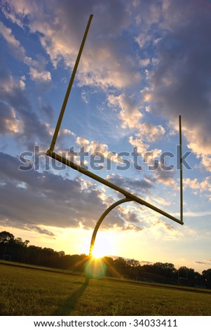 American football goal posts and end zone at sunset over dramatic cloudy sky