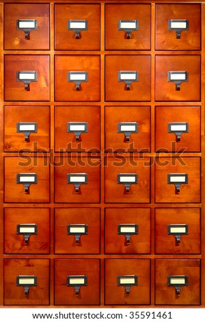 Old fashioned library card filing storage wood cabinet with drawers and index tab inserts on antique metal pulls