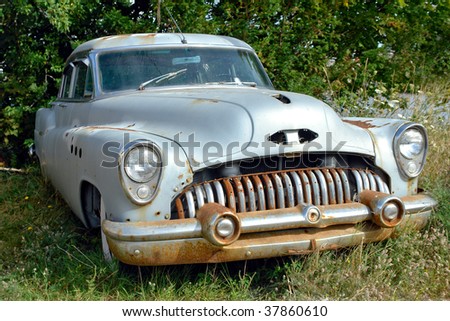 Old abandoned American car rusting on a lot