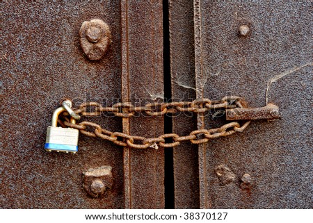 Safety chain and security padlock on a closed old rusty steel door