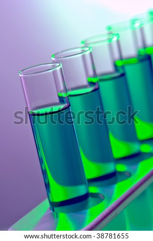 Laboratory glass test tubes filled with green liquid chemical solution on a rack for an experiment in a science research lab