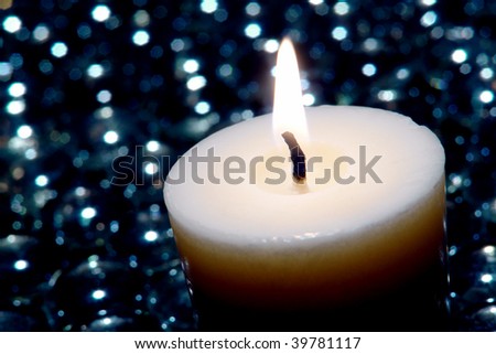 Meditation votive candle burning in a new age Zen inspired bed of shinny black glass jewels