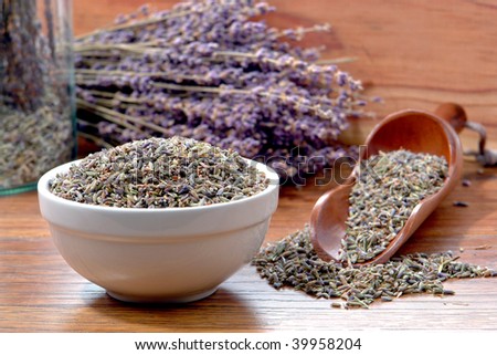 Lavender flower seeds in a bowl with fresh cut purple flowers and mix seed sampler in a wood scoop in an aromatherapy scent and fragrance maker artisan shop