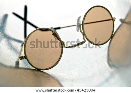 Pair of round spectacle tinted sunglasses on galvanized steel surface